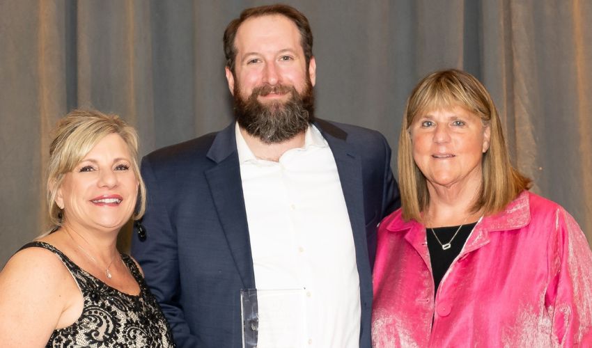 Three associates are holding an award.