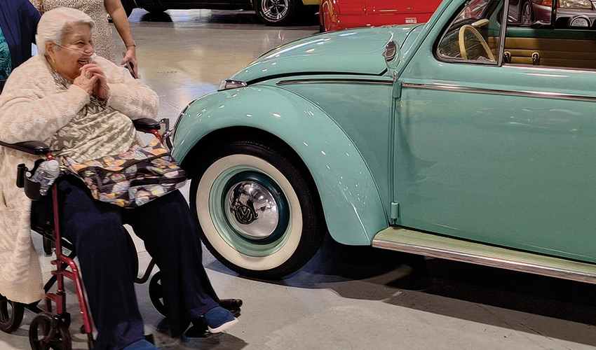 A person in wheelchair next to car.