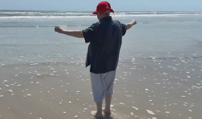 A person standing on the beach with arms outstretched.