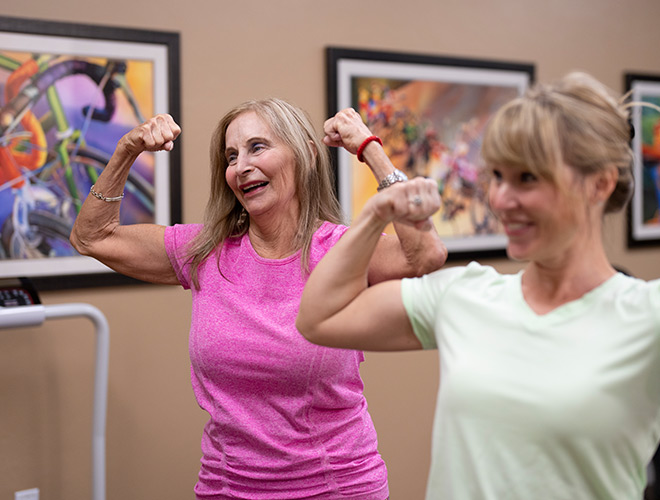 A resident and their trainer flexing in a fitness class.