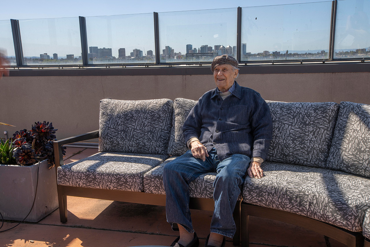 A resident sits on couch on roof top at The Watermark By The Bay.