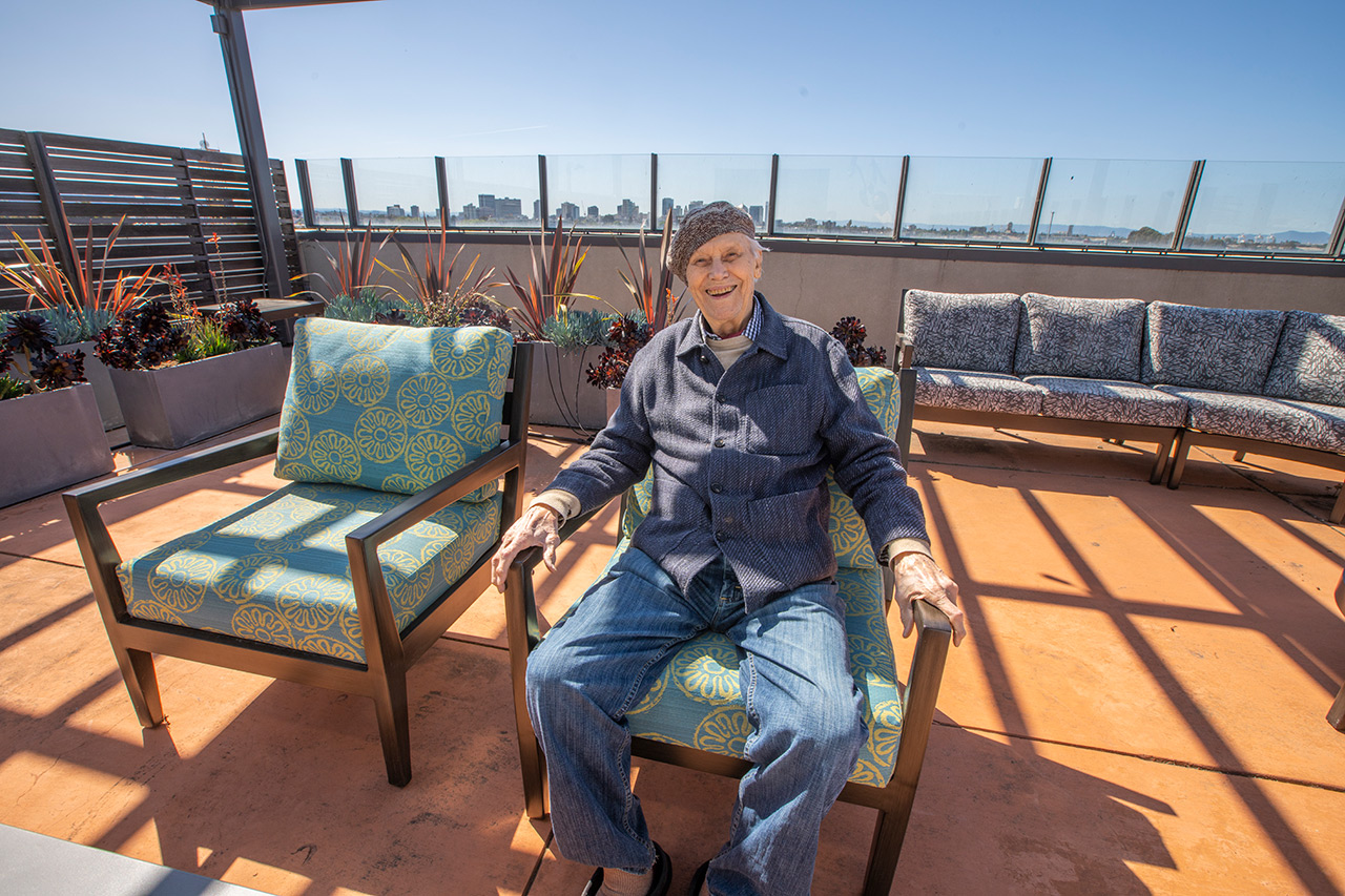 A resident sits on couch on roof top at The Watermark By The Bay.