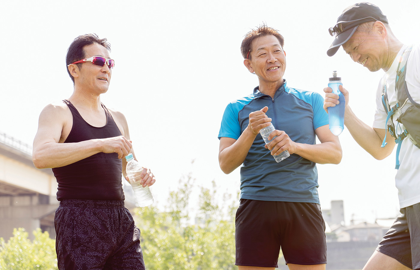 Three people in workout attire chatting outside.