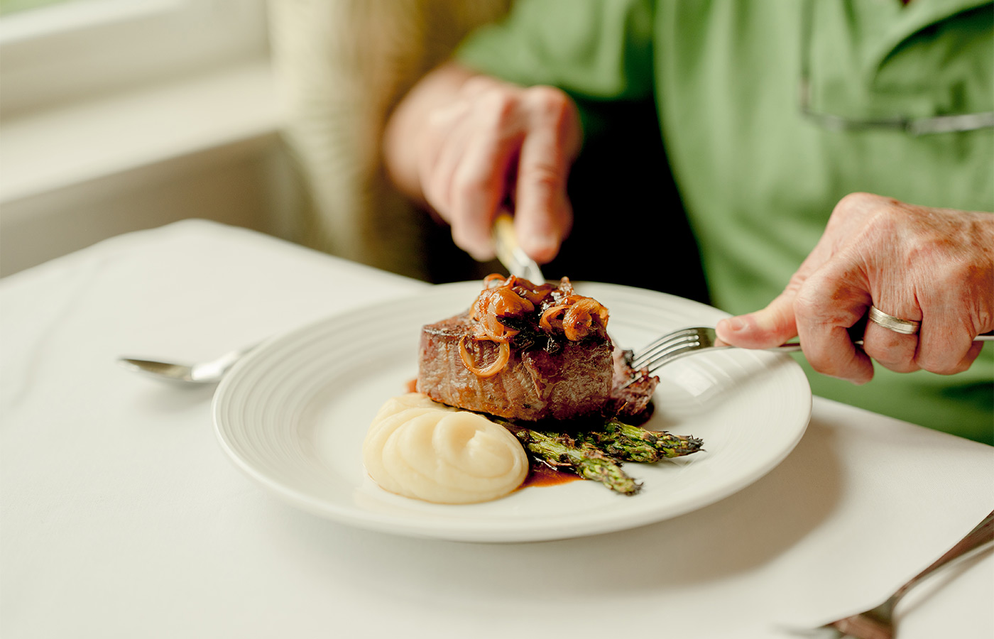 A person cutting into a steak.