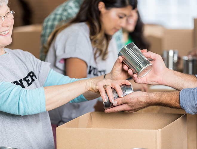 People volunteering taking in canned food.