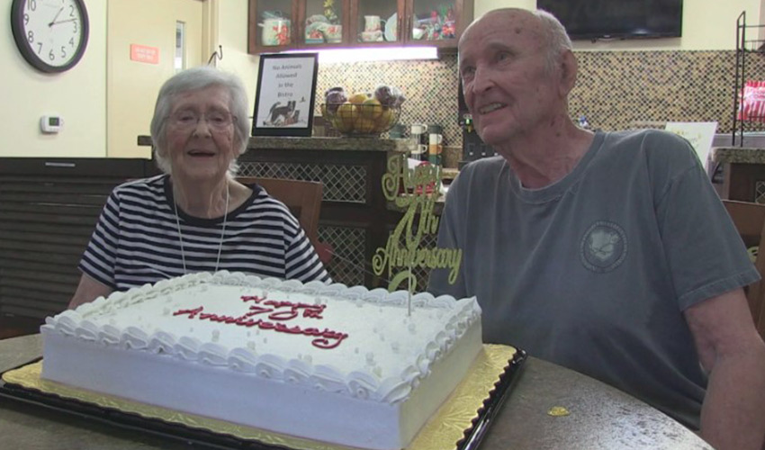 Two people smiling with a large cake.