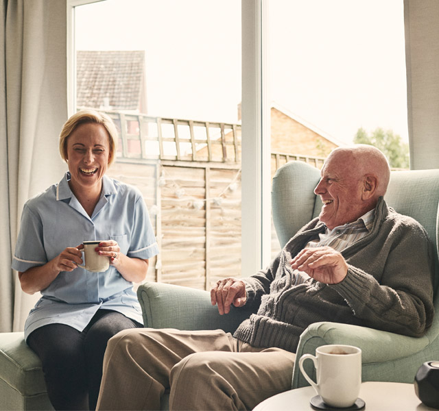 A resident sitting and having a laugh with their nurse.
