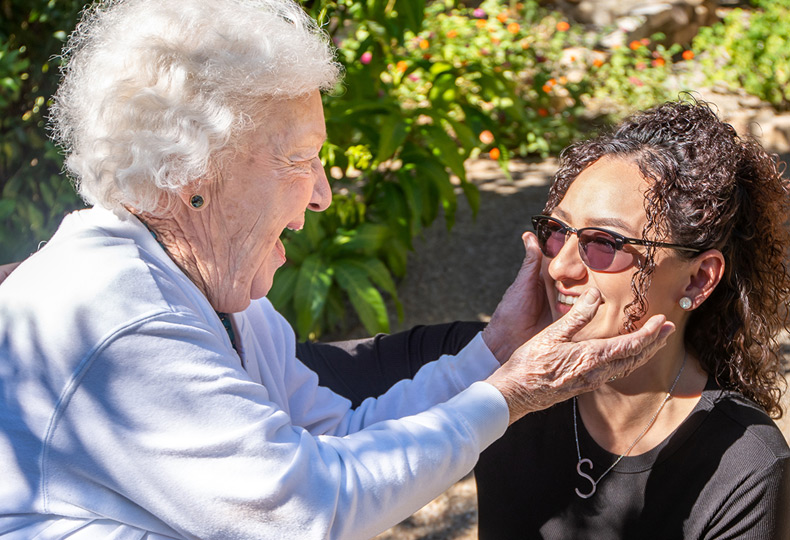 Smiling resident holding a person's face in their hands. 