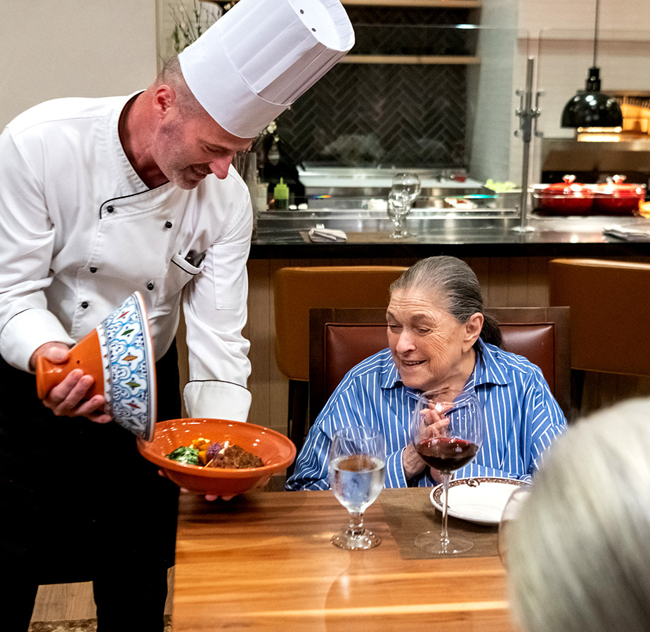 A chef is showing a dish to a resident.