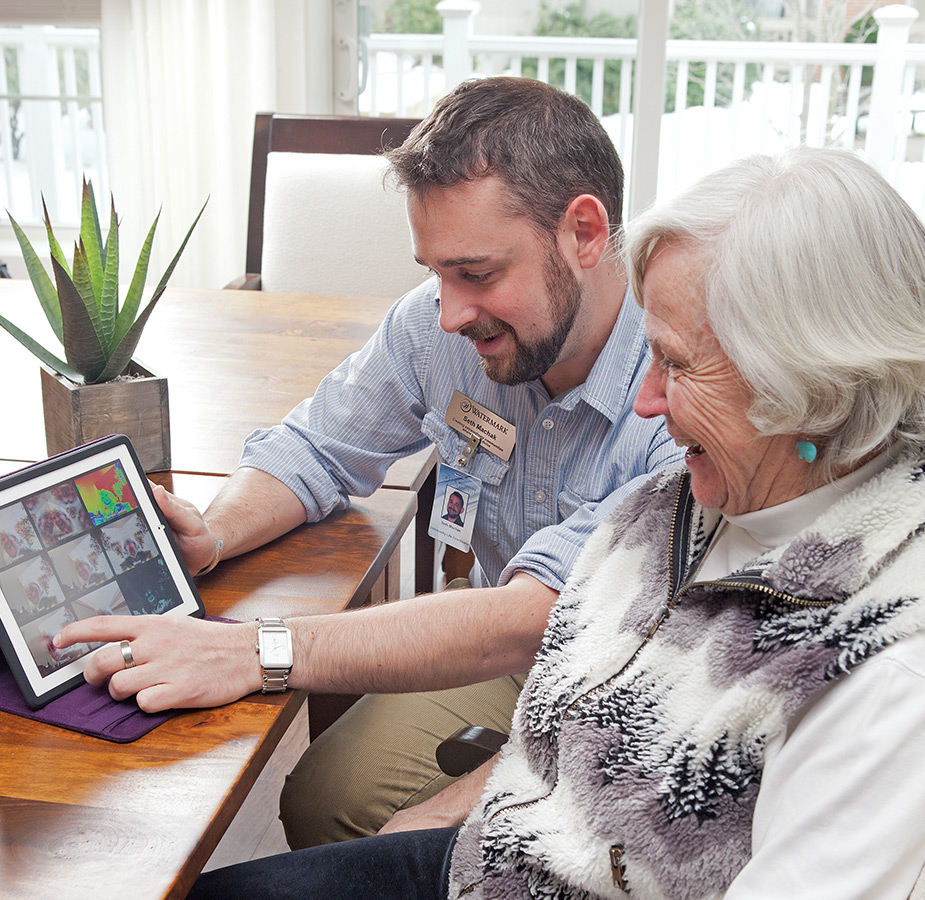 An associate is showing a resident a smart tablet.