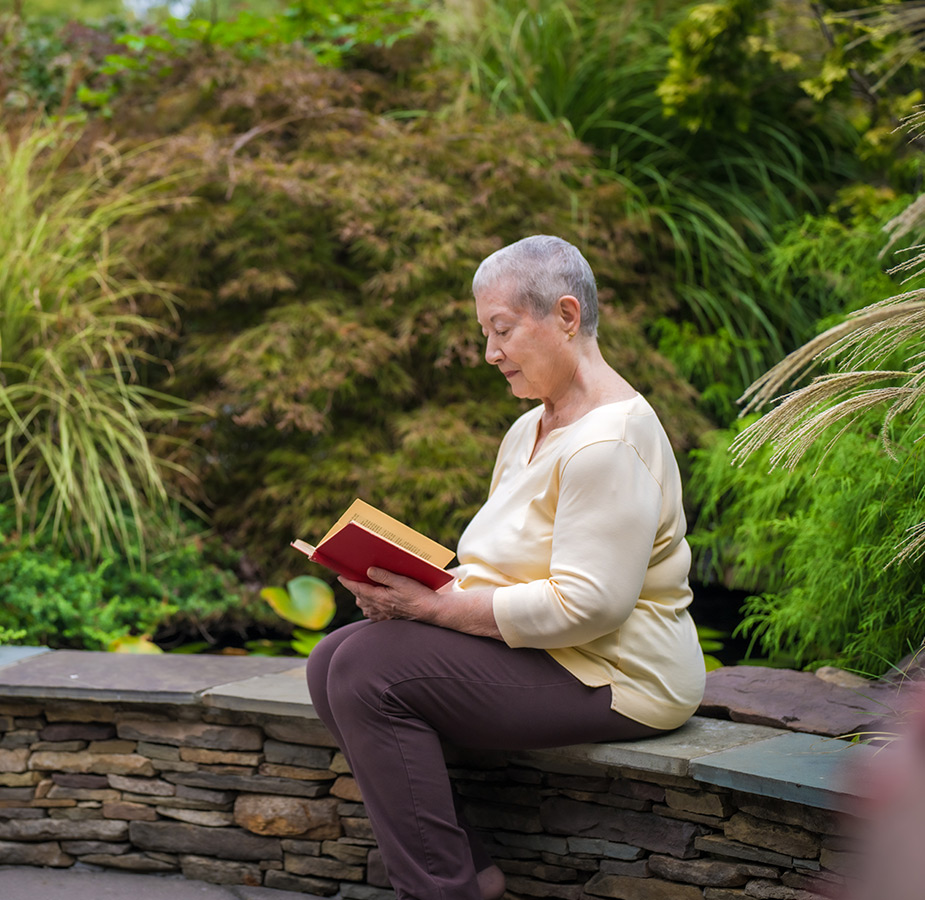 A resident is reading by a koi pond.