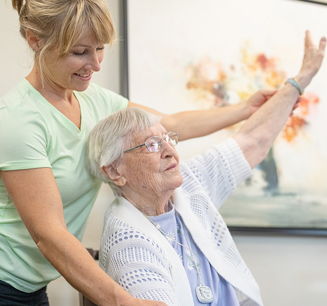 A caregiver is assisting a resident stretch.
