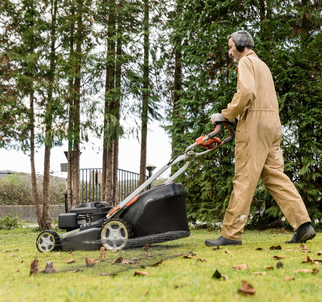 A worker mows the lawn outdoors, representing the time and effort that home maintenance can require.