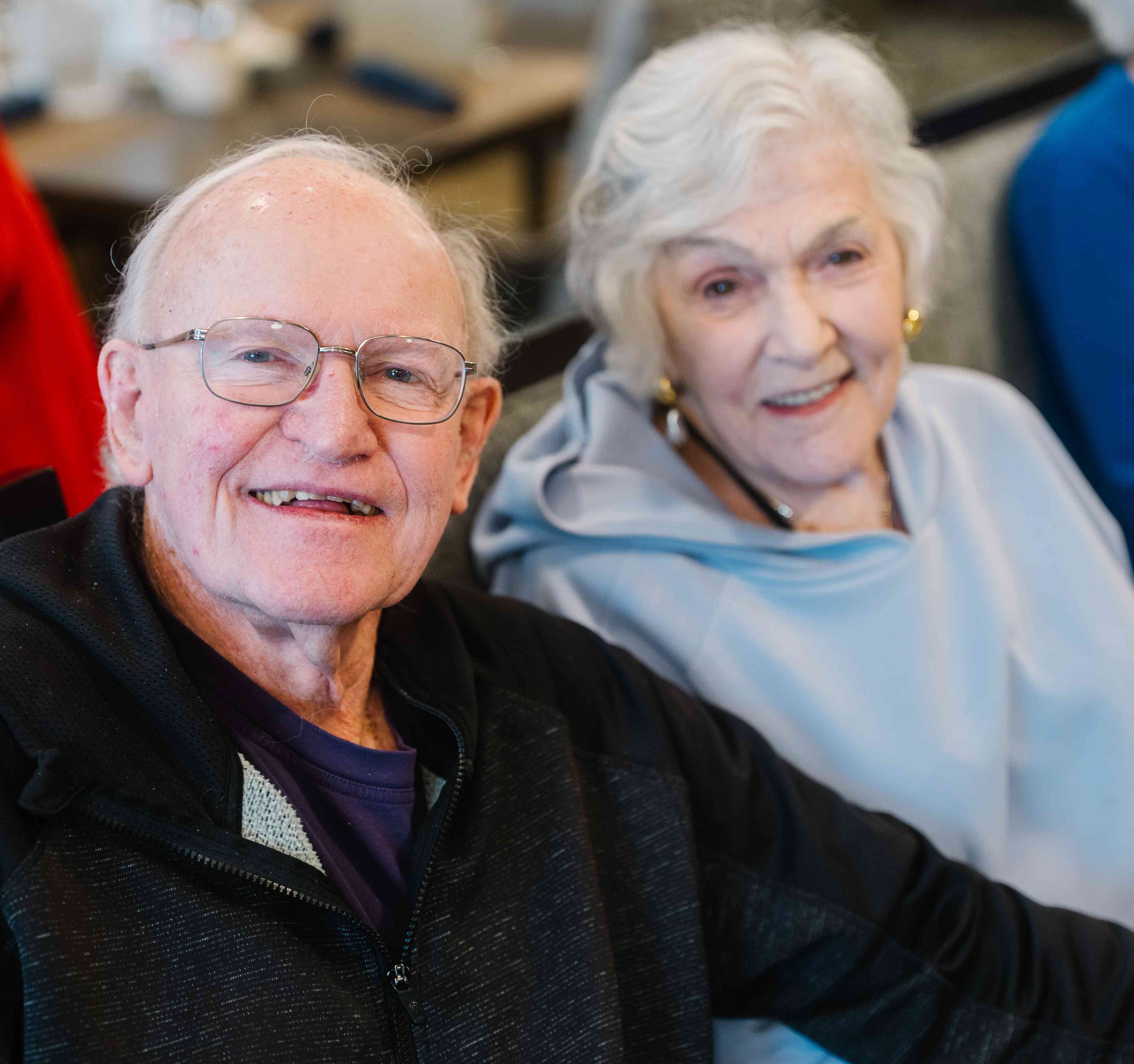 Two residents sit side by side, smiling warmly during a social gathering.