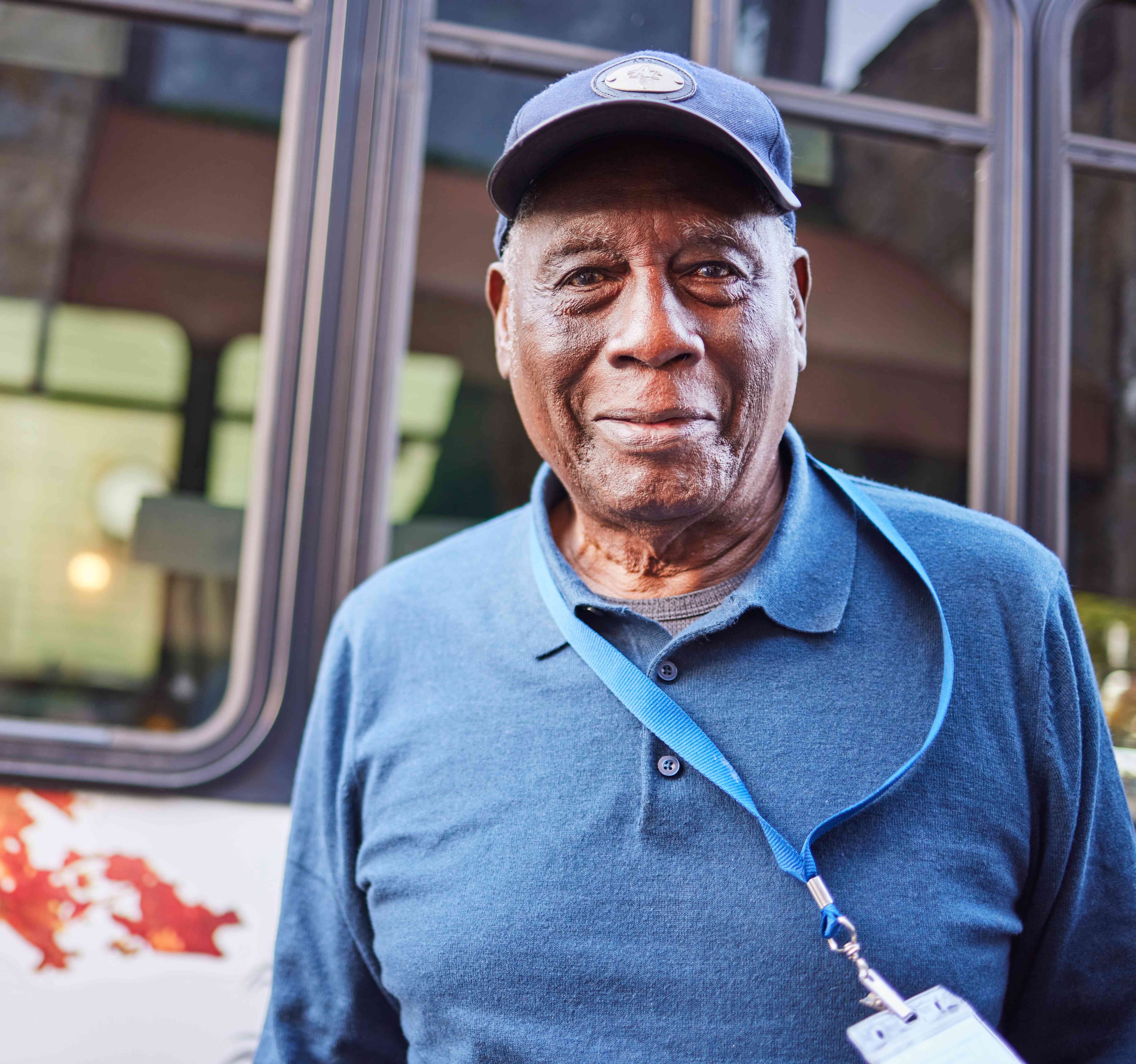 A resident stands smiling near the community bus, capturing a sense of connection, independence, and everyday ease.