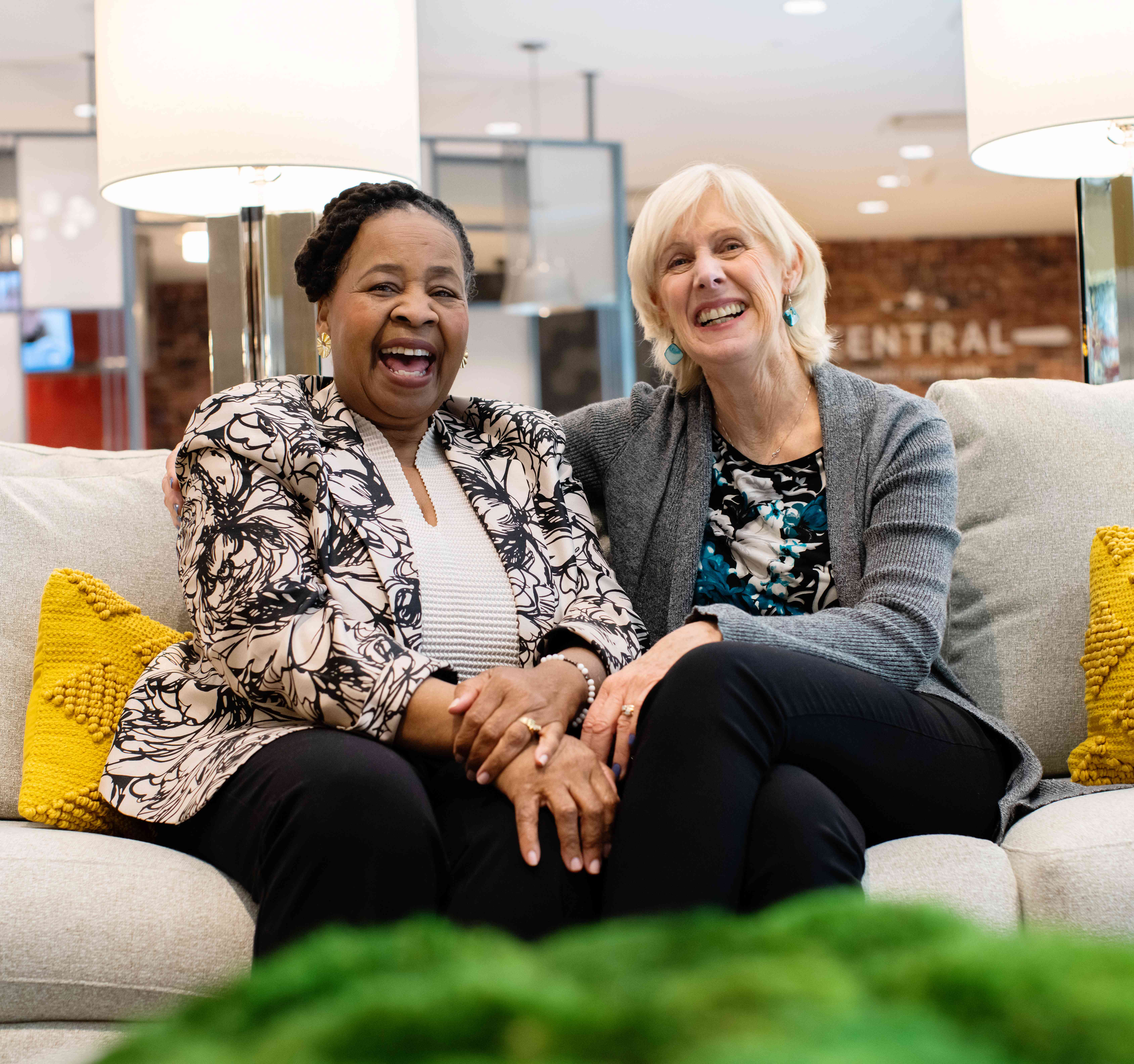 Two residents sitting on a couch and laughing.