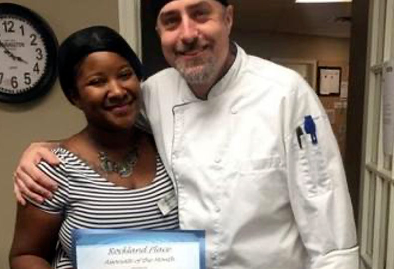 Tyhisha, a Watermark associate, is standing with a chef smiling.