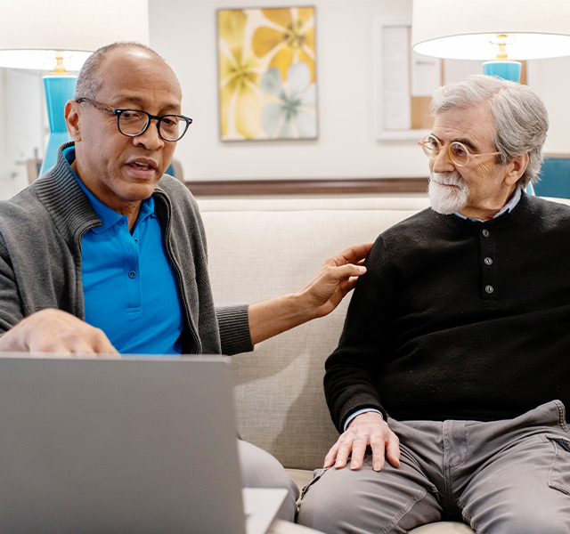 A person showing another something on the computer.