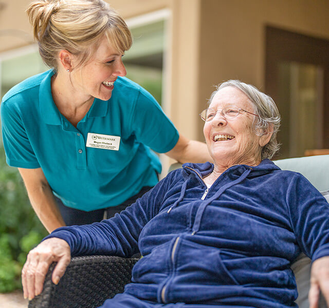 A resident is outside chatting with a caregiver.