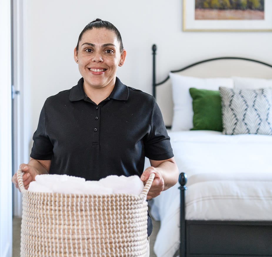 A person is holding a basket of clean towels.