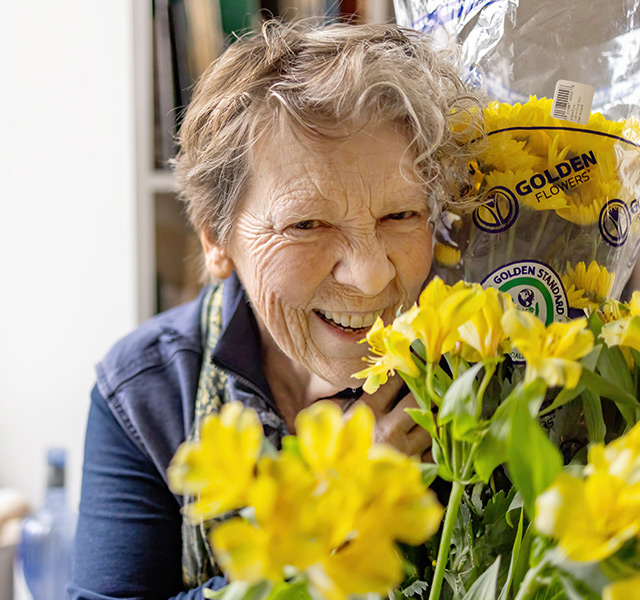 A person smiling with a bouquet of flowers.