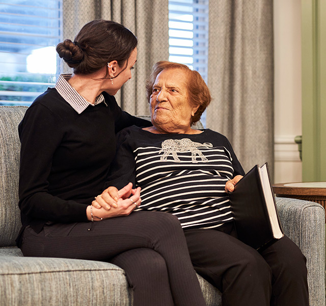 A person sitting with a resident on the couch.