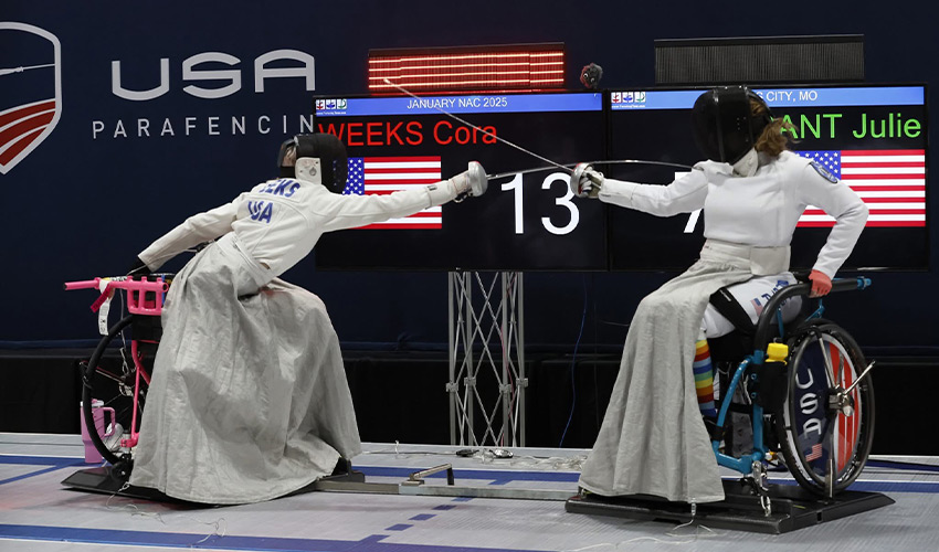 Two people in wheelchairs fencing.