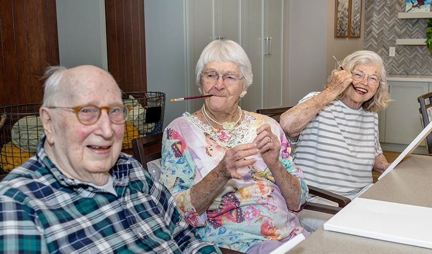 Three people goofing around with paintbrushes.