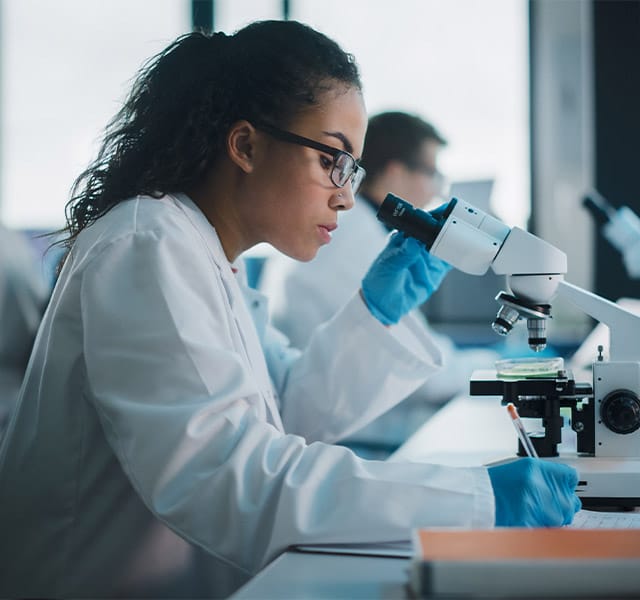 A person is looking into a telescope in a lab.