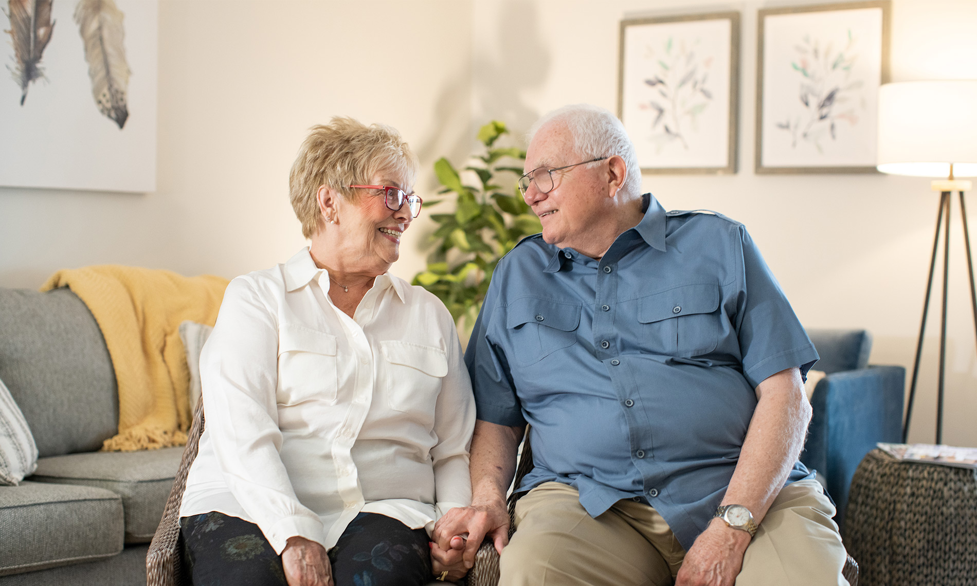 A couple sitting on chairs holding hands.