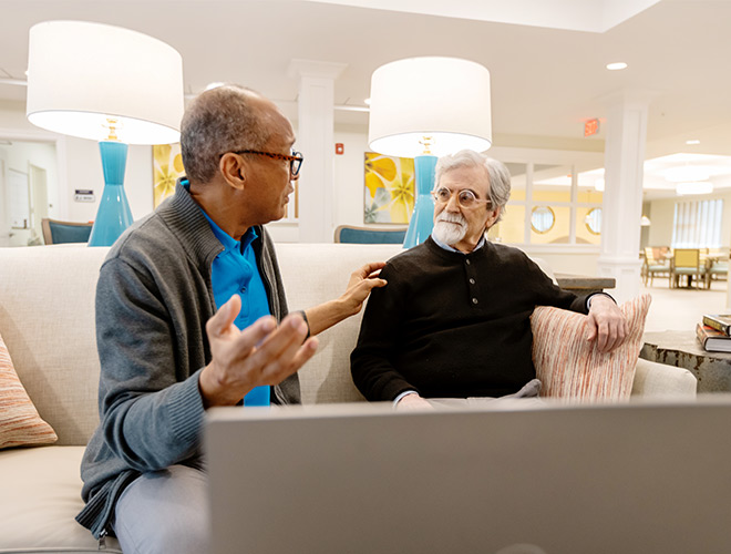 Two people talking near a computer.