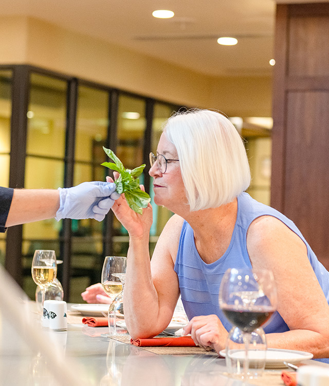 A person smelling fresh basil leaves.