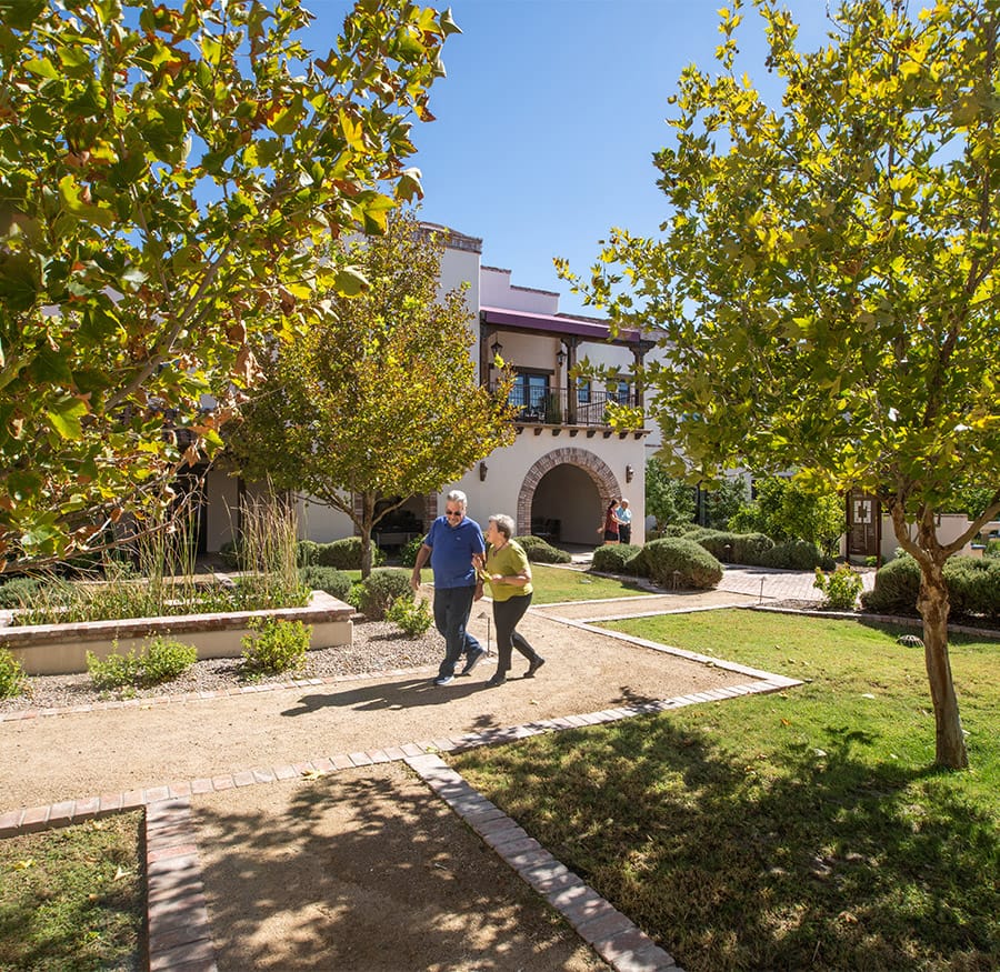 Two residents are walking in a courtyard.