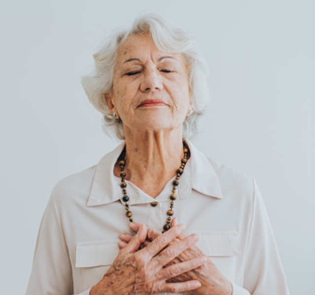 Person with their eyes closed and hands on their heart. Very peaceful.