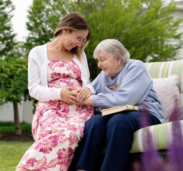 Associate who is pregnant with resident who is touching her belly.