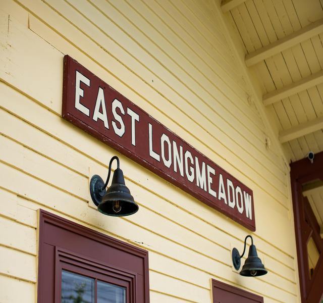 Side of yellow building that has a sign reading East Longmeadow.
