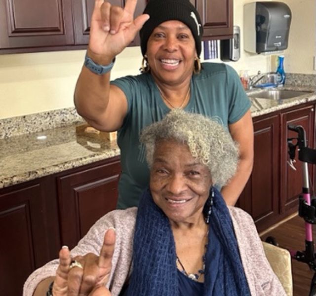 Two people signing "I love you" in ASL.