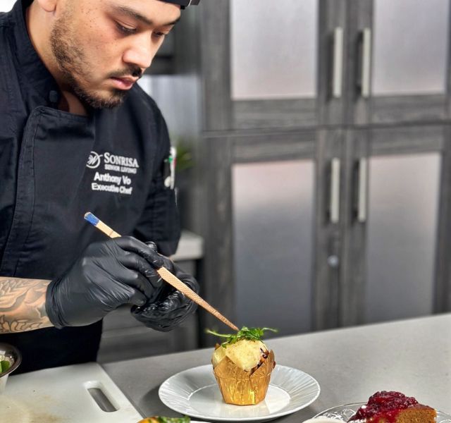 A chef finishing a dish in the kitchen.