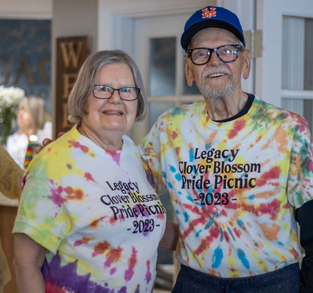 Two people wearing tie-dyed Pride shirts.