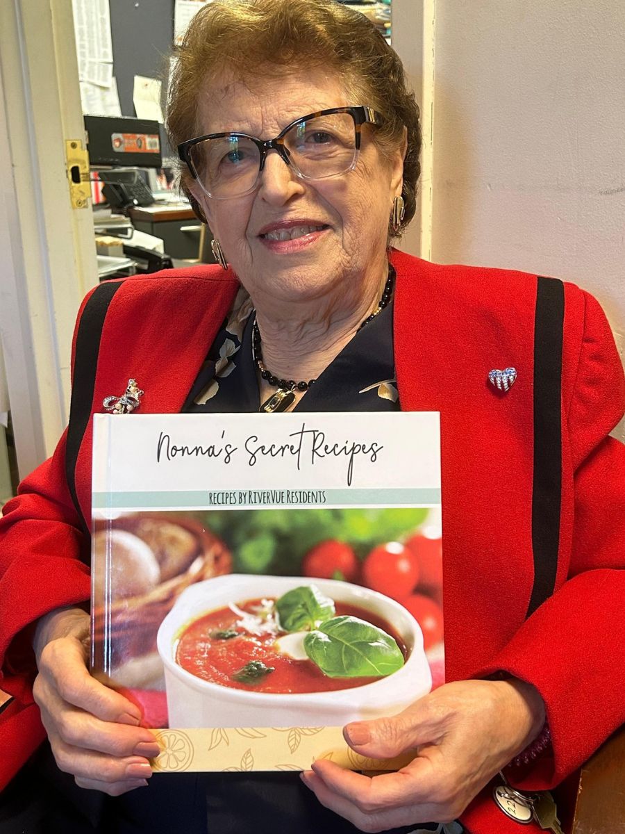 Helen, a resident, is holding a cookbook.