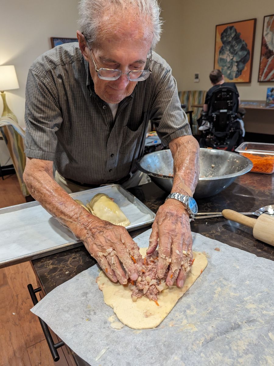 Tony, a resident, placing a filling in rolled out dough.