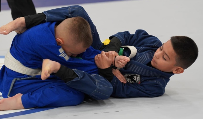 Two kids doing jiu jitsu.