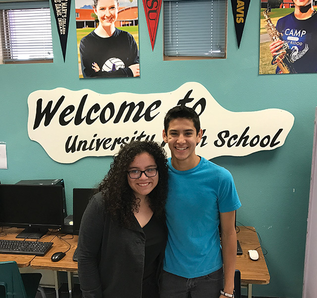 Two people standing together in a school classroom.
