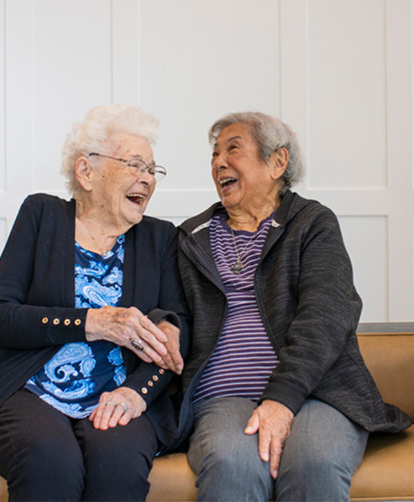 Accordion image Two residents sitting on a bench laughing together.
