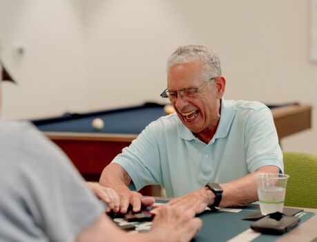 Members playing a game at a card table with a pool table in the background.