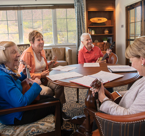 A group of women residents playing music around a table.