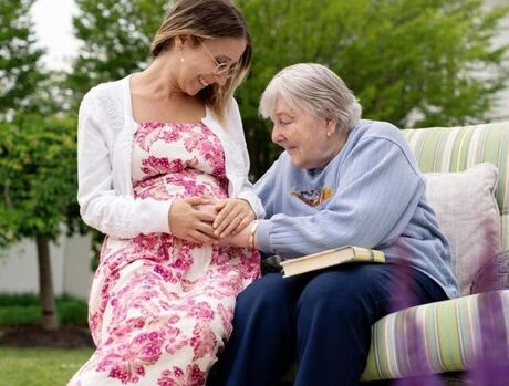 Associate who is pregnant with resident who is touching her belly.