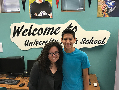 Two people standing together in a school classroom.