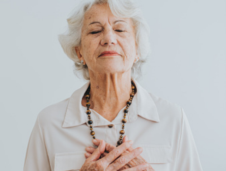 Person with their eyes closed and hands on their heart. Very peaceful.