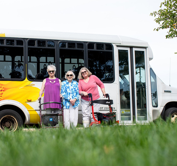 Three residents are standing by a bus.
